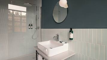 Un baño con lavamanos blanco, espejo y ducha.