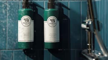 To flasker af Parco 1923 hotelkollektions shampoo og balsam på en blå flisovg.