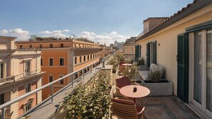 A balcony with outdoor seating, overlooking a cityscape with historic buildings. - Cloud 7 Roma Hotel (Rome)