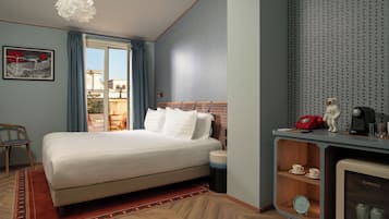 Camera d'albergo con un letto grande, una scrivania con un computer, una macchina per il caffè piccola e vista sulla città.