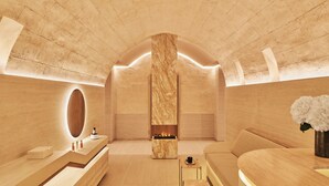 Un spa moderno con un pilar de mármol, un sofá, una mesita con una taza y un espejo.