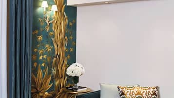 Una habitación con un sofá verde, una mesita auxiliar dorada y una araña.