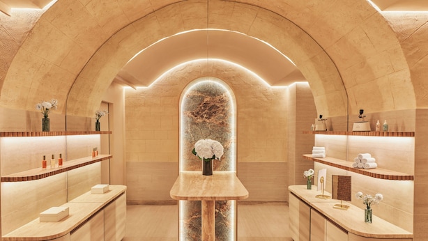 Un interior tipo spa, con un arco de piedra central, mostrador de recepción de madera y encimeras de mármol.