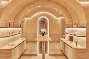 A spa-like interior with a central stone archway, wooden reception desk, and marble countertops. - Maison Barrière Vendôme (Paris)