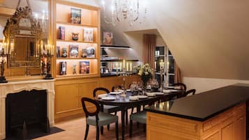 A dining area with a chandelier, a fireplace, and a bookshelf with books and decorative items.