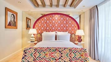 A hotel room with a large bed, two bedside lamps, a patterned headboard, and framed artwork on the walls.