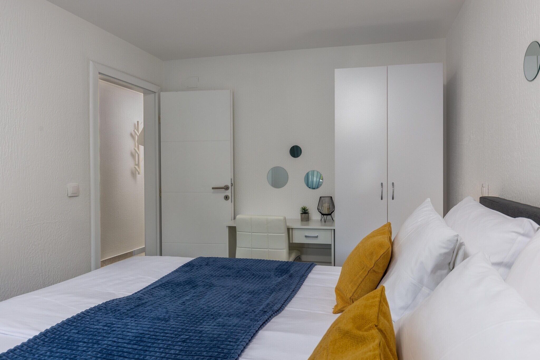 A bedroom with a bed, a desk, and a wardrobe.