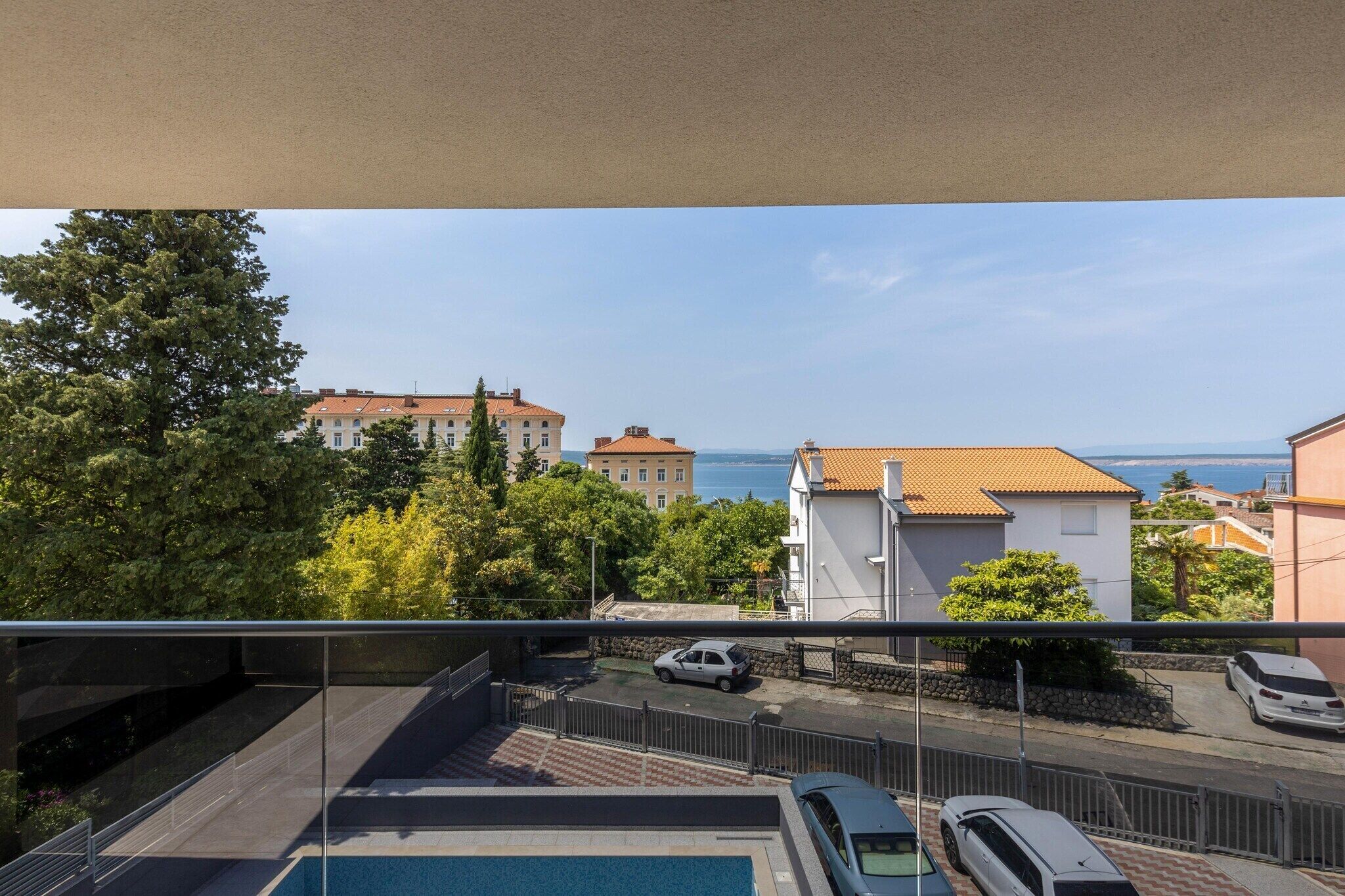 Een balkon met uitzicht op een woongebied, met huizen en een waterpartij.