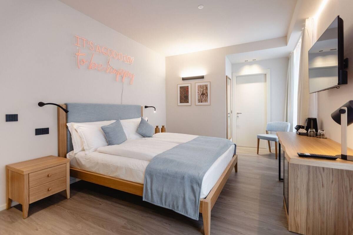 A modern bedroom with a bed, bedside tables, a desk, and a mirror.