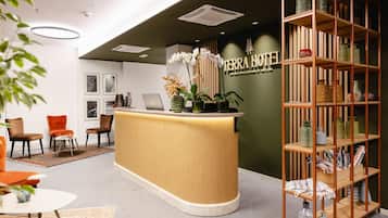 Zona de recepción del Terra Hotel, con un mostrador curvo, una estantería con objetos decorativos y un diseño interior moderno.