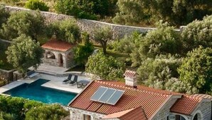 Une villa en pierre dotée d’une piscine, de plusieurs balcons et d’un panneau solaire.