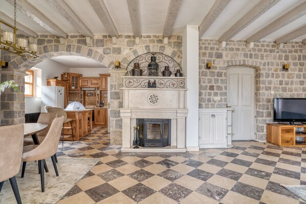 A spacious living room with a stone wall, a fireplace, and a checkered floor. - Spacious Villa Olive Grove with private Pool (Budva)