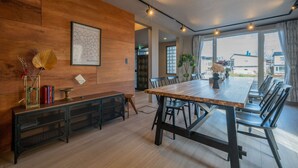 Un comedor moderno con una larga mesa de madera, sillas negras y una consola metálica negra con adornos.