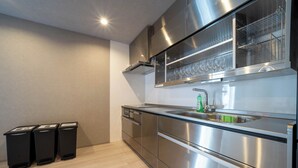 Una cocina moderna con electrodomésticos de acero inoxidable, una vinoteca empotrada y tres cubos de basura.