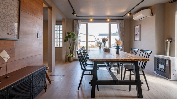 Un comedor moderno con una larga mesa de madera, sillas negras y una planta en maceta.