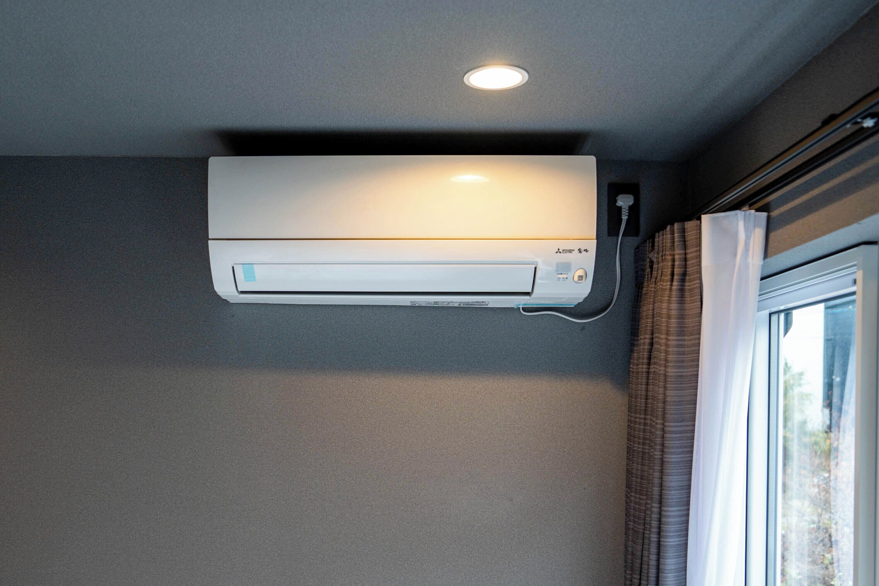 A wall-mounted air conditioner with a control panel and a power cord.