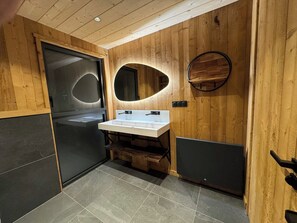 A modern bathroom with a wooden wall, a sink with a mirror, and a door.