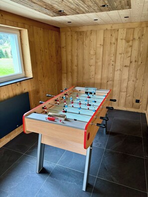 Una mesa de fútbolín en una habitación con paredes de madera y una ventana.