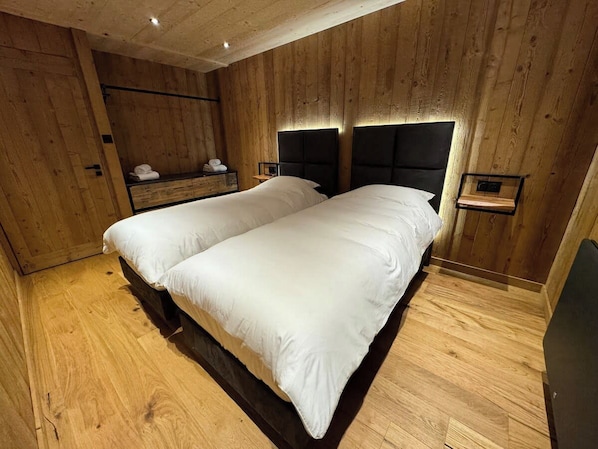A wooden-paneled room with a bed, bedside tables, and a bench.