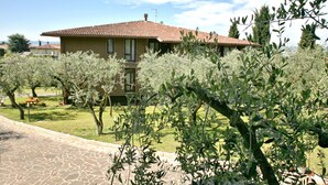 A house with a tiled roof, surrounded by olive trees and a stone pathway. - Residence Uliveto (Garda)