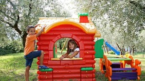 A colorful playhouse with a red and yellow roof, green and purple steps, and a small window. - Residence Uliveto (Garda)