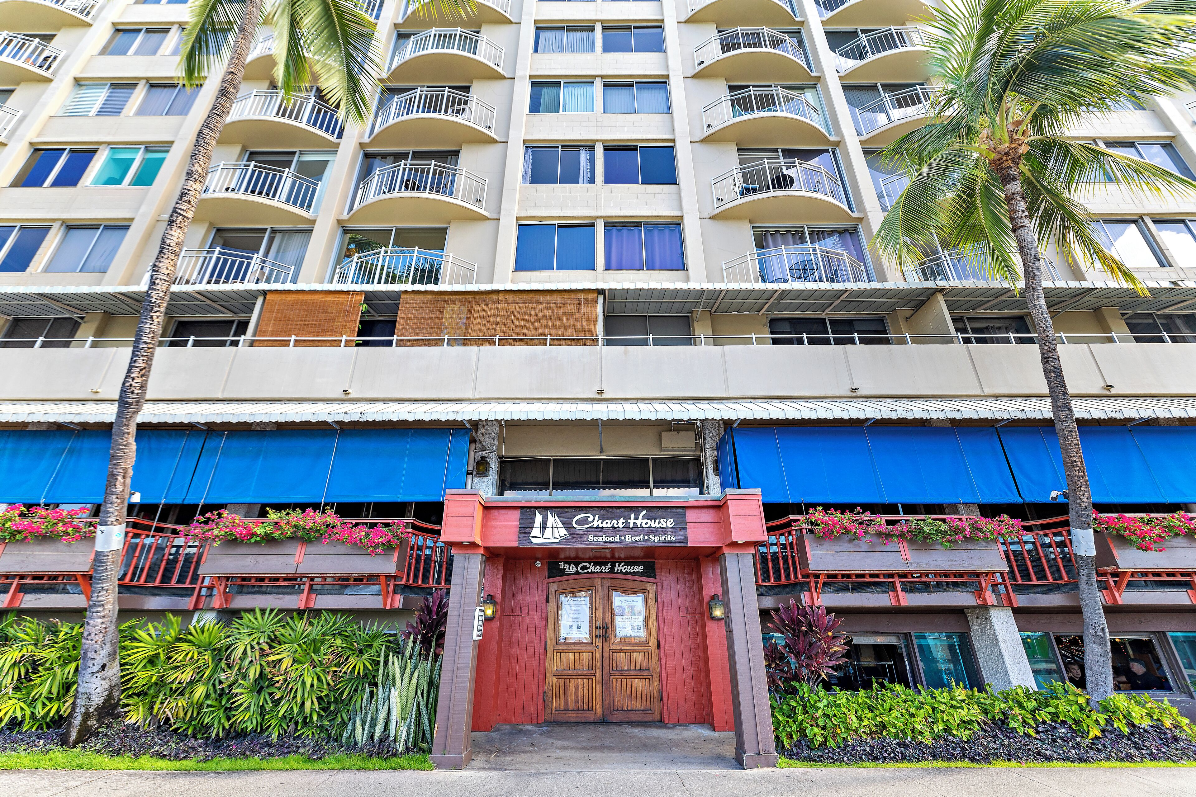 A hotel with a two-story structure, balconies with railings, and a prominent entrance with signage.