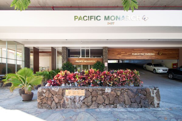 A building entrance with a sign reading "Pacific Monarch 2427" and a "Public Pay Parking" sign.