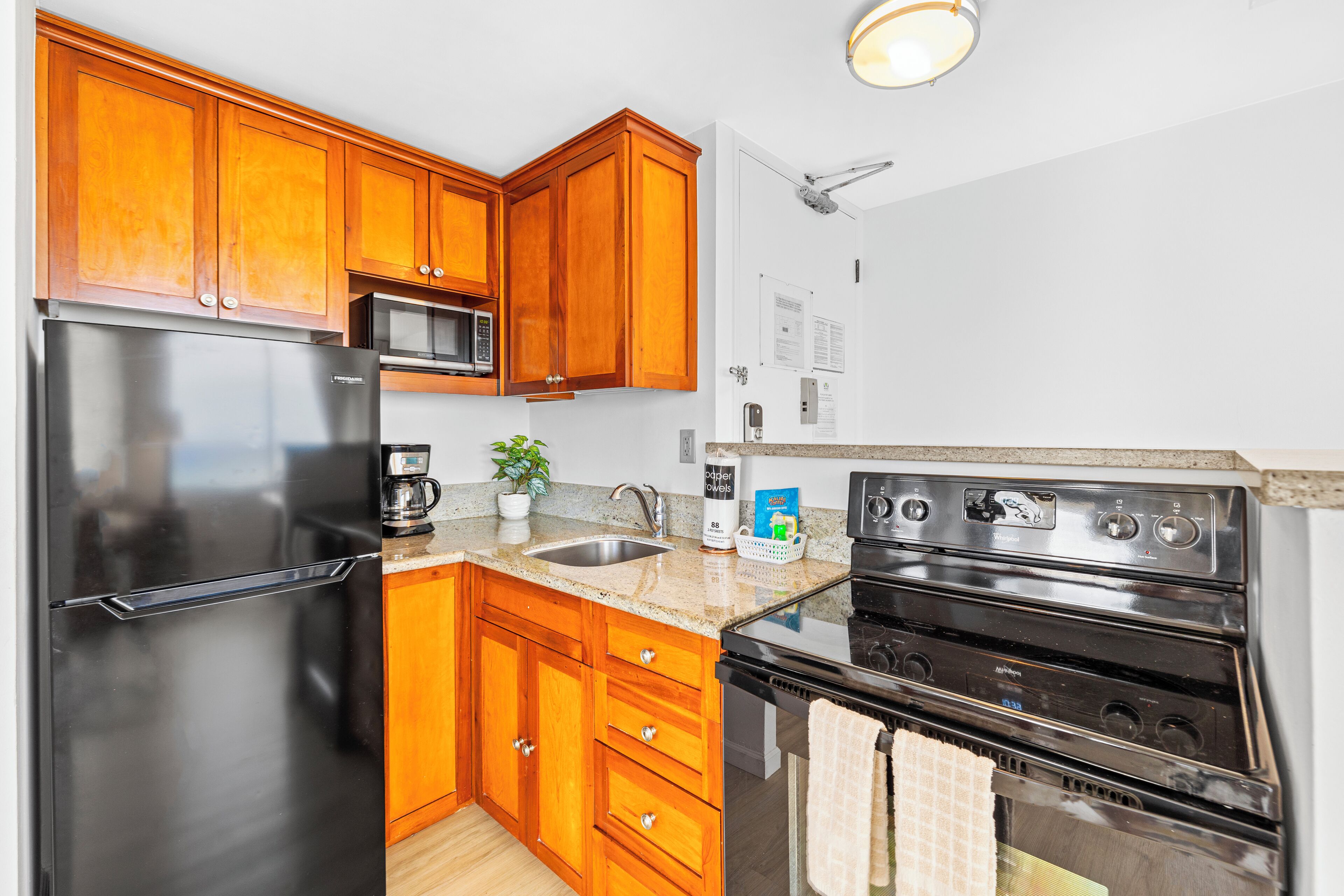 A kitchen with wooden cabinets, a stainless steel refrigerator, a microwave, a coffee maker, and a stove.