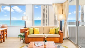 A modern living room with a sofa, two lamps, a coffee table, and a view of the ocean.