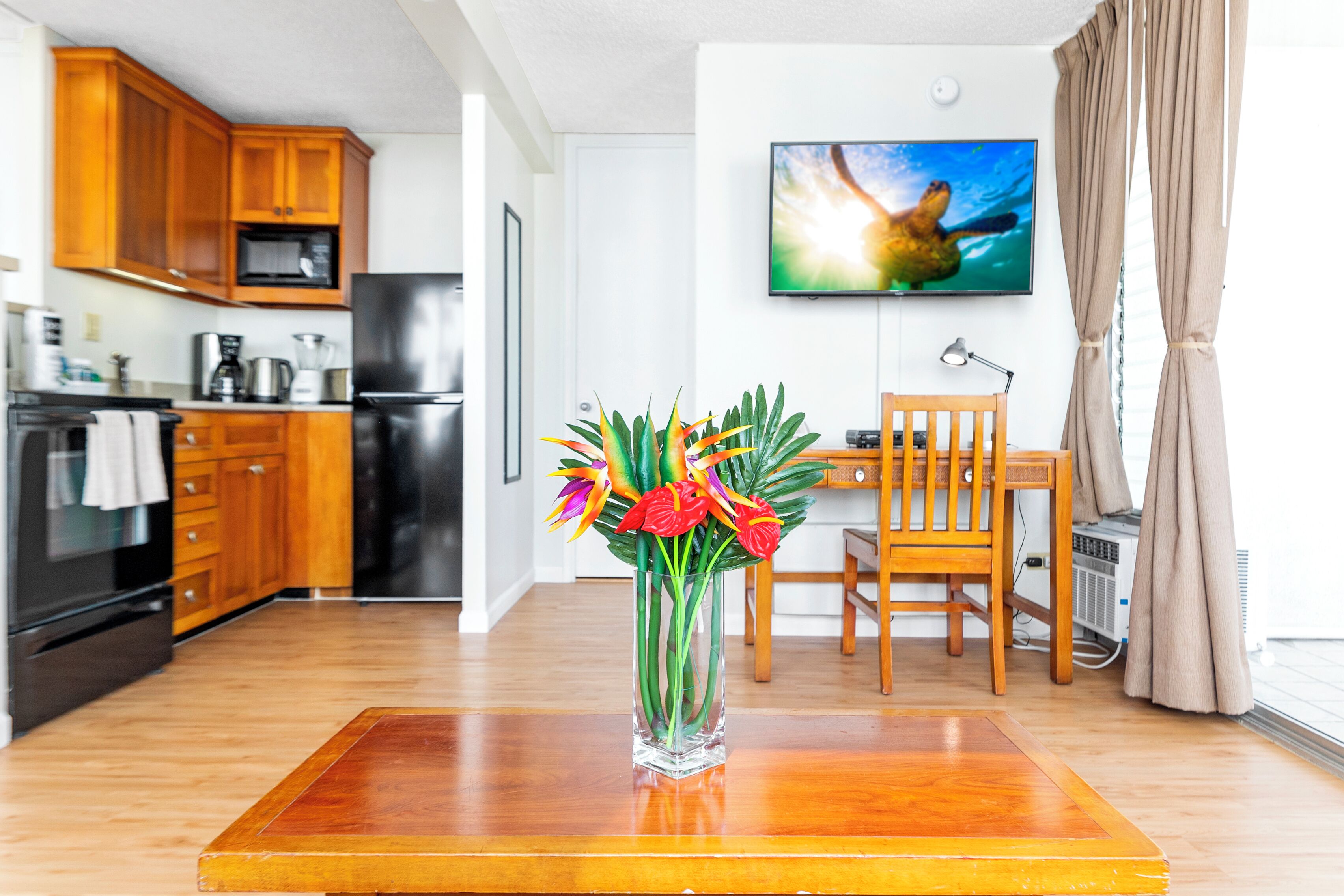 A modern kitchen with wooden cabinets, a black refrigerator, and a dining area with a wooden table and chairs.