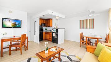A modern living room with a dining area, kitchen, and a TV mounted on the wall.