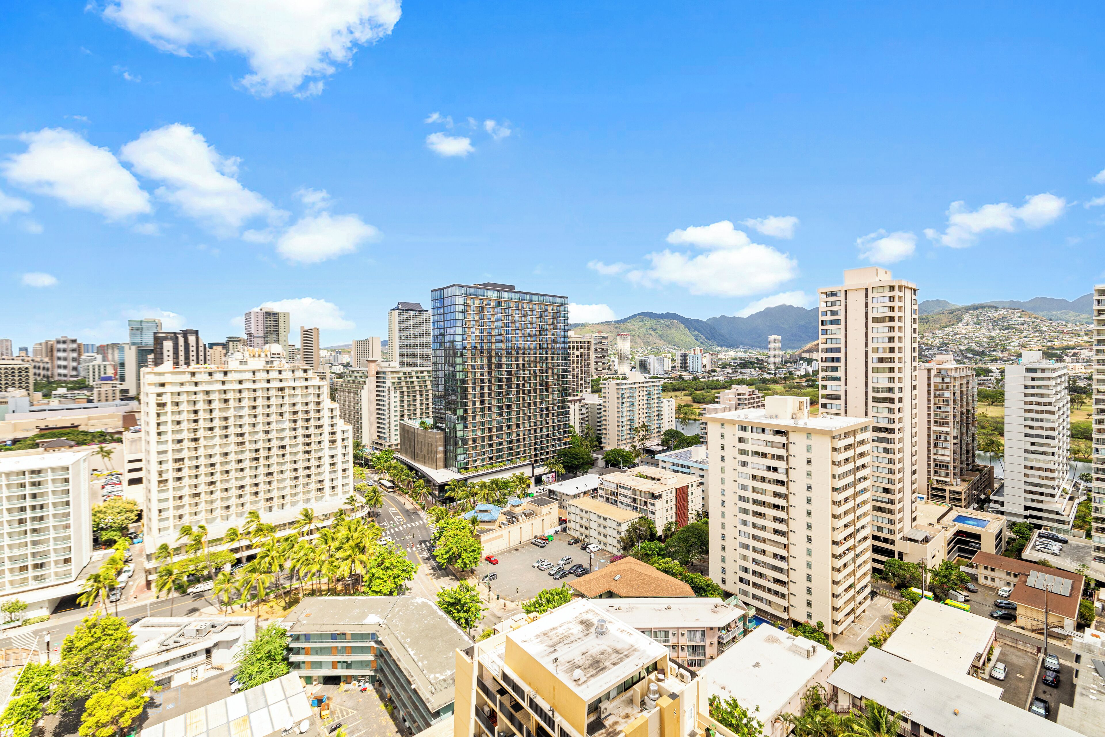 A high-rise hotel with multiple floors, a central courtyard, and a view of the surrounding cityscape and mountains.