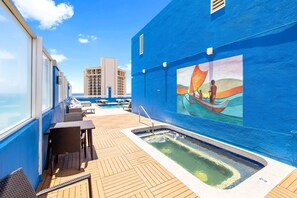 A cruise ship deck with a swimming pool, lounge chairs, and a mural of a sailboat.