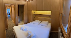 A hotel room with a large bed, wooden wardrobe, and a shower area.