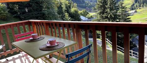 A wooden deck with a table and chairs, overlooking a mountainous landscape.