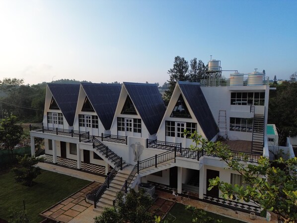 A modern building with a symmetrical design, featuring multiple levels and a central staircase. - The Novel Holiday Resorts (Tirupattur)
