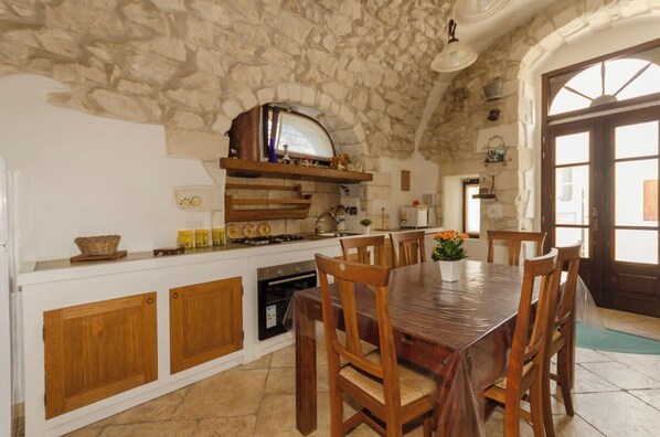 Una cocina rústica con paredes de piedra, armarios de madera y una gran mesa de comedor.