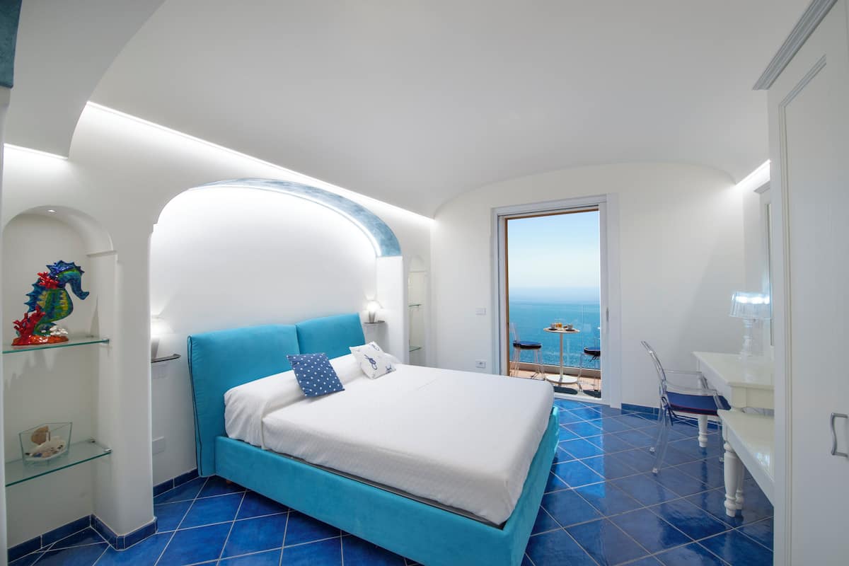 Une chambre avec un lit, un bureau et une vue sur la mer.