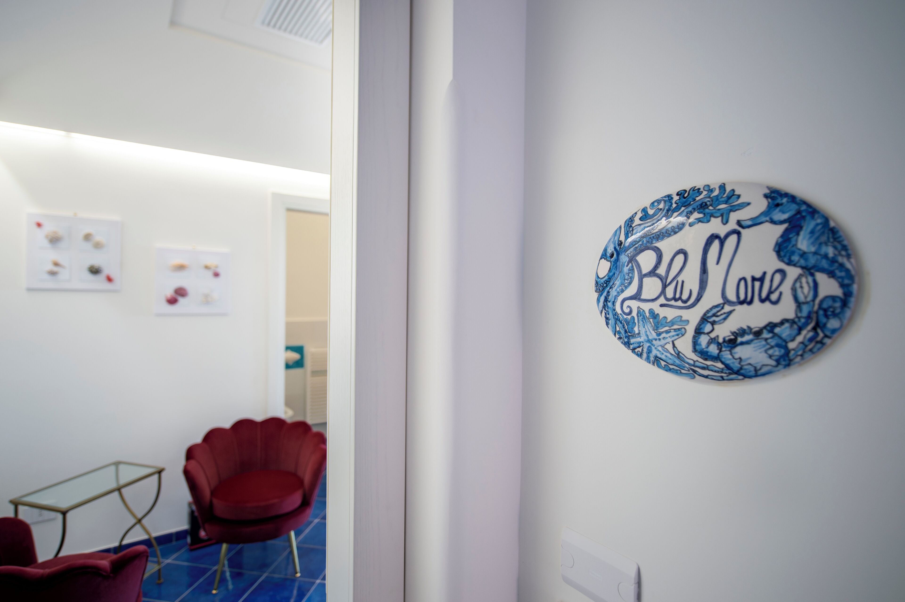 A room with a red chair, a small table, and a wall-mounted sign that reads "Blue House."
