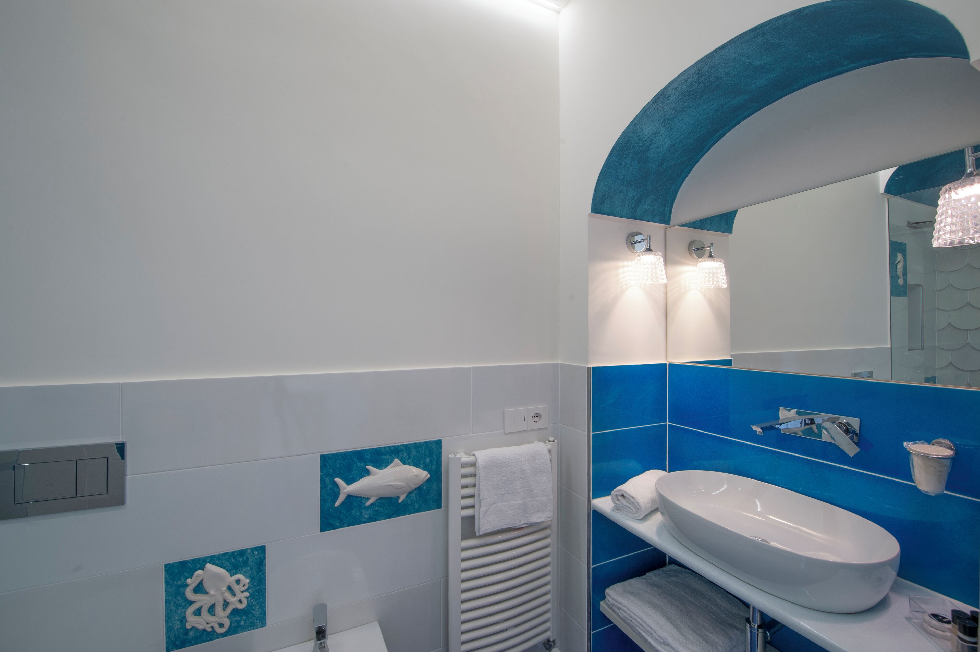 Un baño moderno con un lavamanos blanco, azulejos azules y un espejo grande.