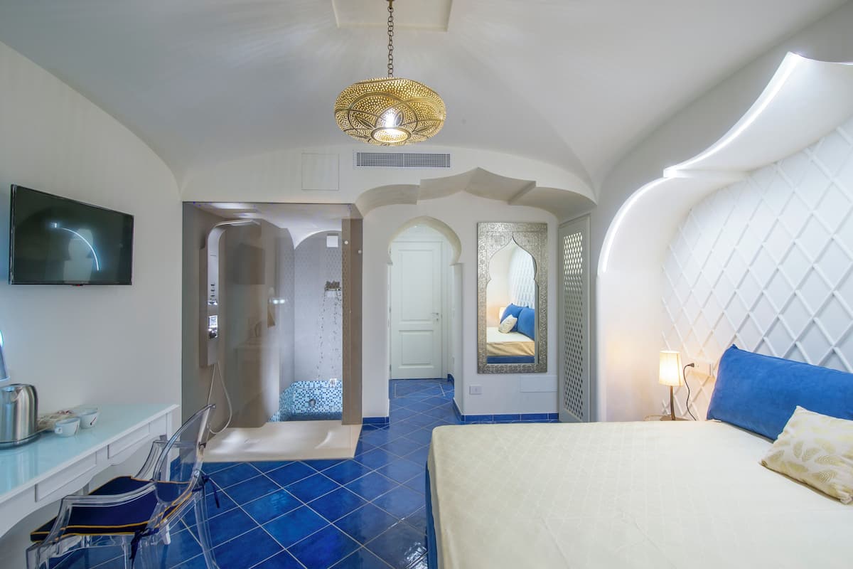 Une chambre d’hôtel avec un grand lit, une télévision, une douche et un bureau avec une chaise.