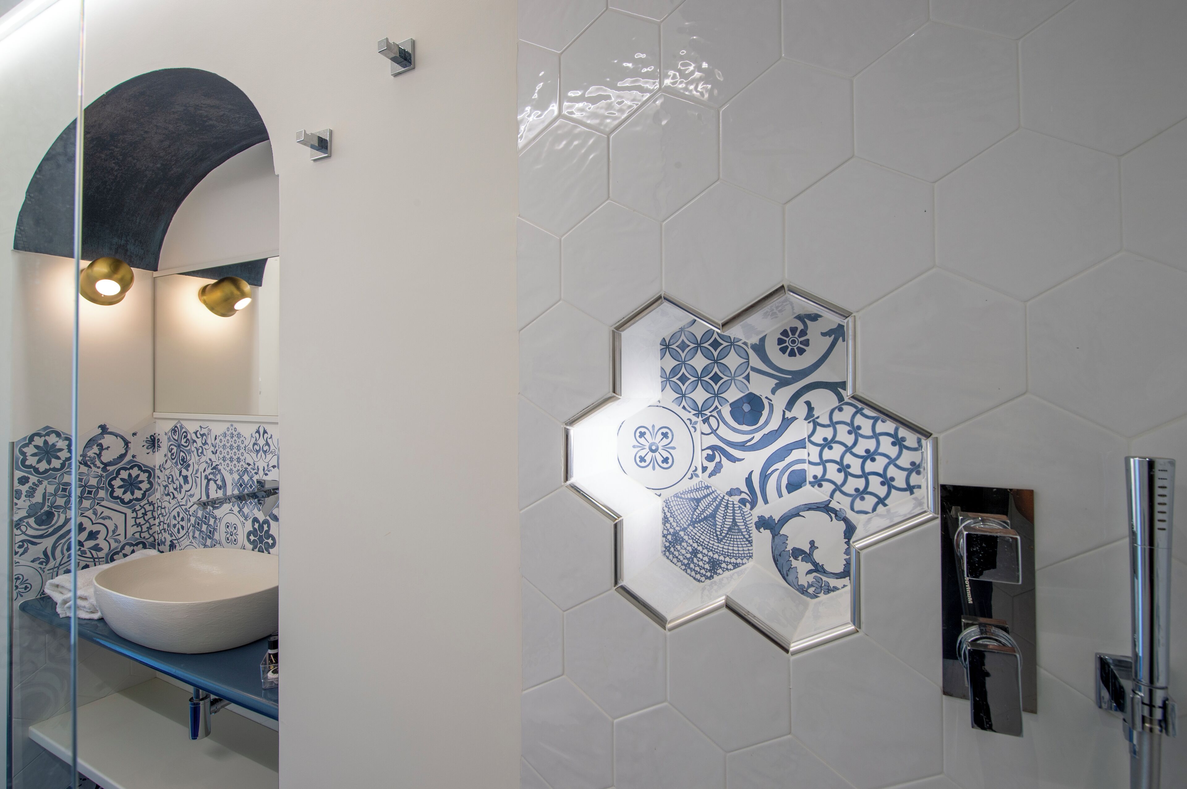 Une salle de bain avec un grand lavabo blanc, un pare-chocs en carreaux bleus et blancs, et un espace douche doté d’un robinet chromé.