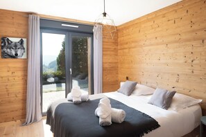 A bedroom with a large bed, a wooden wall, a window with curtains, and a painting of a wolf. - L'Edelweiss - Luxury chalet with Jacuzzi & Sauna, Gérardmer (Gérardmer)