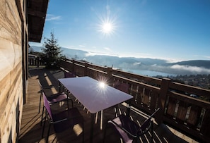 A wooden deck with a table and chairs, overlooking a mountainous landscape with a clear sky. - L'Edelweiss - Luxury chalet with Jacuzzi & Sauna, Gérardmer (Gérardmer)