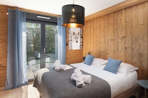 A bedroom with a large bed, a wooden headboard, a wall-mounted fox head decoration, and a sliding glass door leading to an outdoor area. - L'Edelweiss - Luxury chalet with Jacuzzi & Sauna, Gérardmer (Gérardmer)