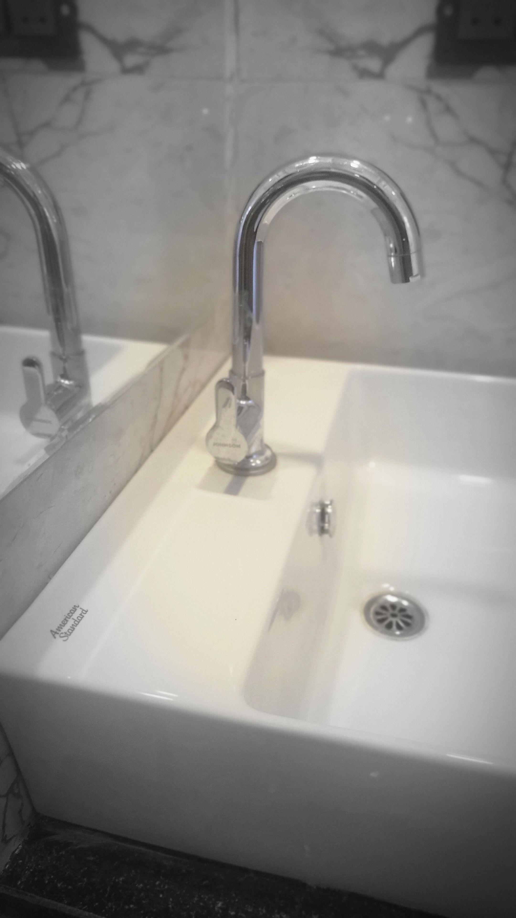 A white bathroom sink with a single faucet and a drain.