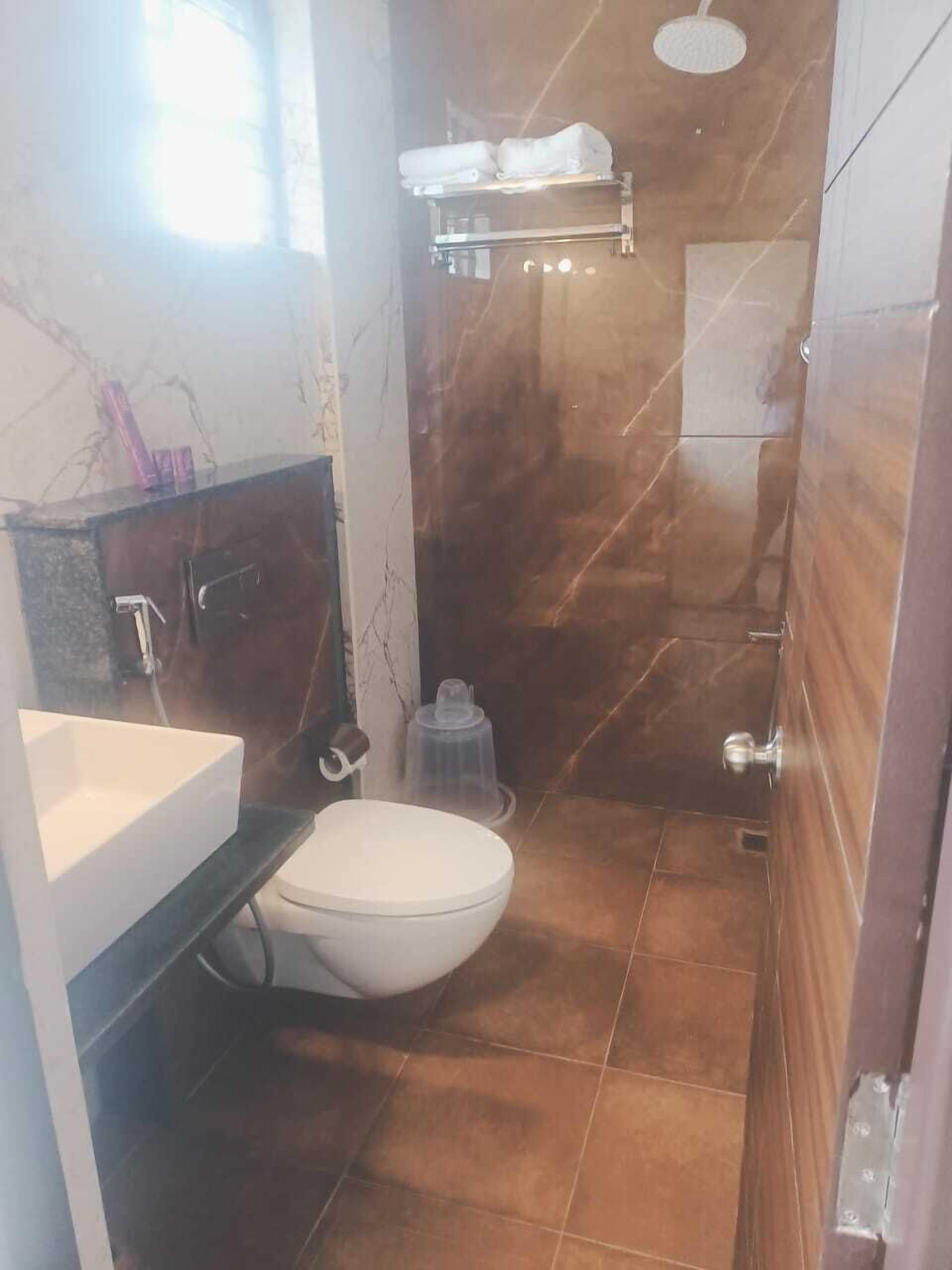 A bathroom with a white toilet, a sink, a shower, and a towel rack.