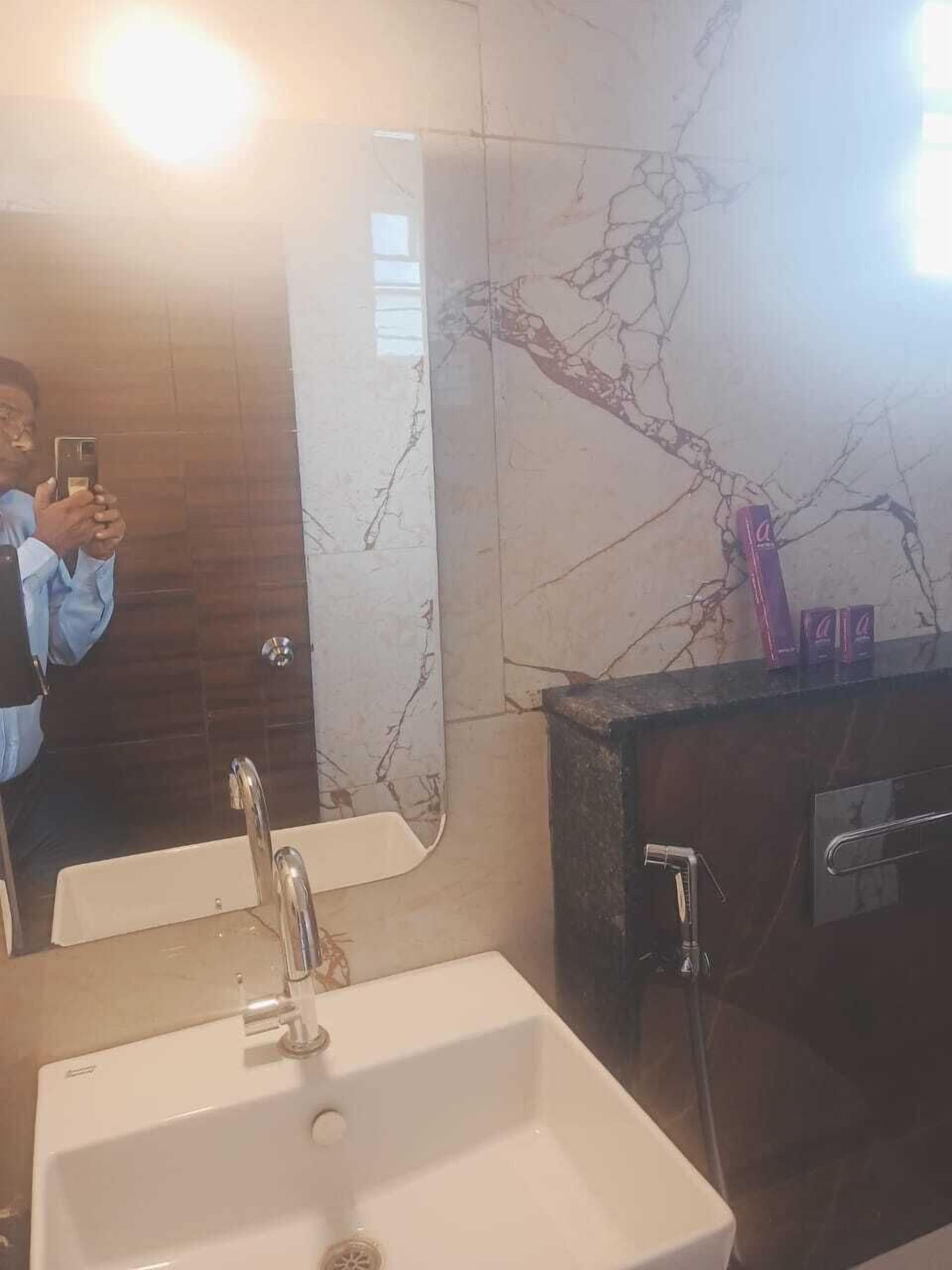 Un baño con un lavabo blanco, un espejo y una pared de mármol.