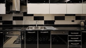 A modern kitchen with black and white checkered backsplash, stainless steel appliances, and a built-in oven. - Hotel Mimani (Berat)