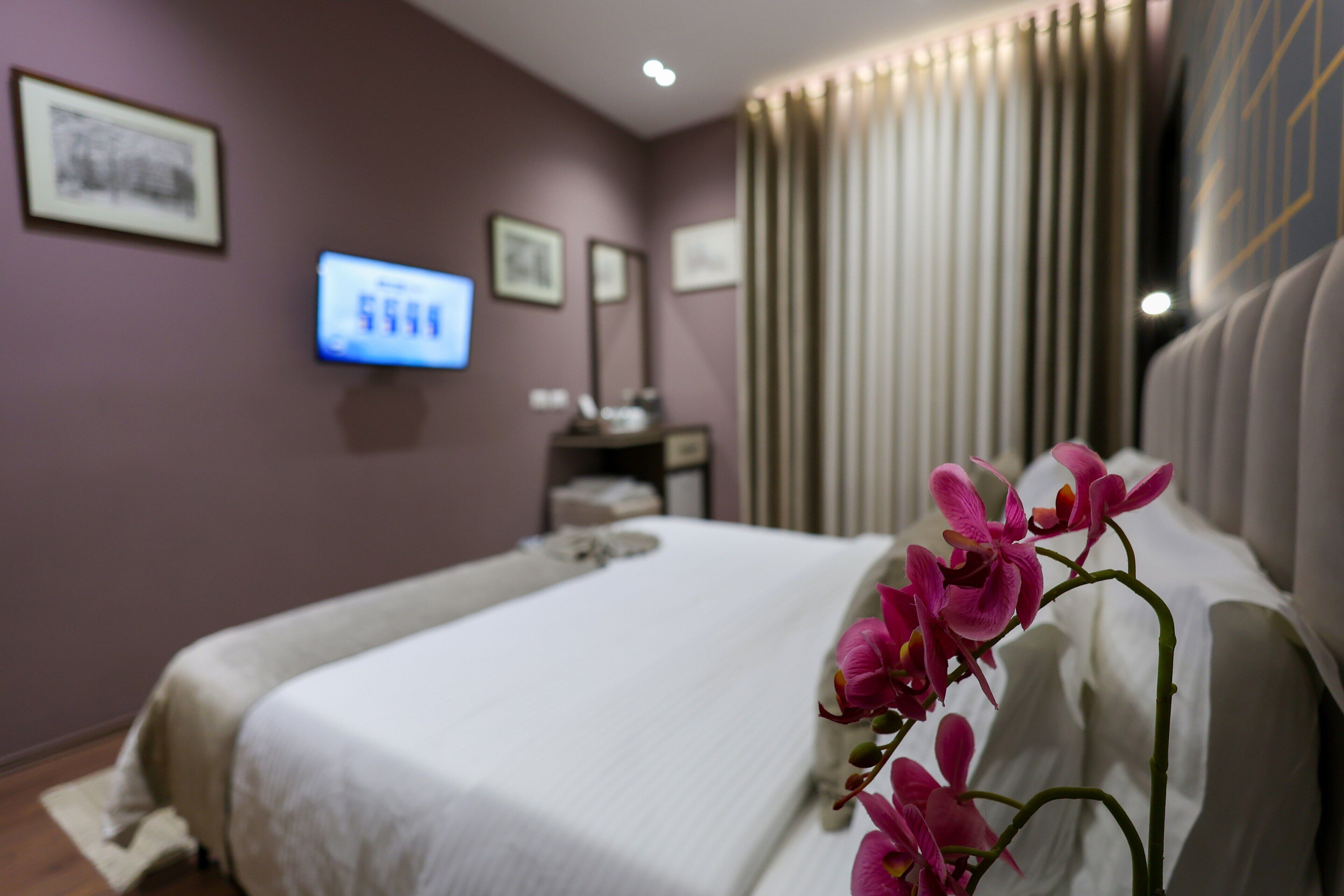 A hotel room with a bed, a television, and a window with curtains.